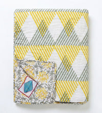 Bild in Galerie-Viewer laden, Detail der Wende-Funktion – die Sunnie Chintz Decke kombiniert moderne Rauten mit einem edlen gelben Blumenmuster auf der Rückseite.