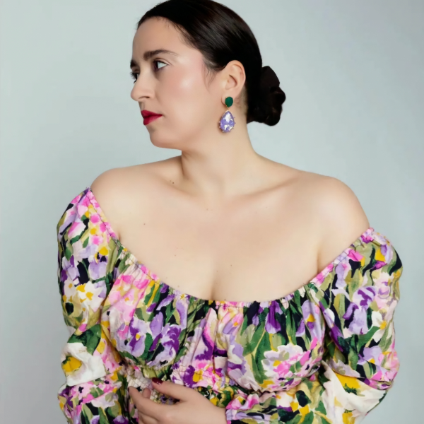 Model trägt grün-lila AMARI Mojave Ohrringe zu einem schulterfreien Blumenkleid.