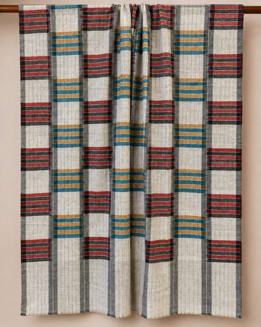 ARLO Pashmina-Schal auf Creme mit grauen Linien und Streifenblöcken in Rot, Petrol und Ocker, über eine Stange gelegt.