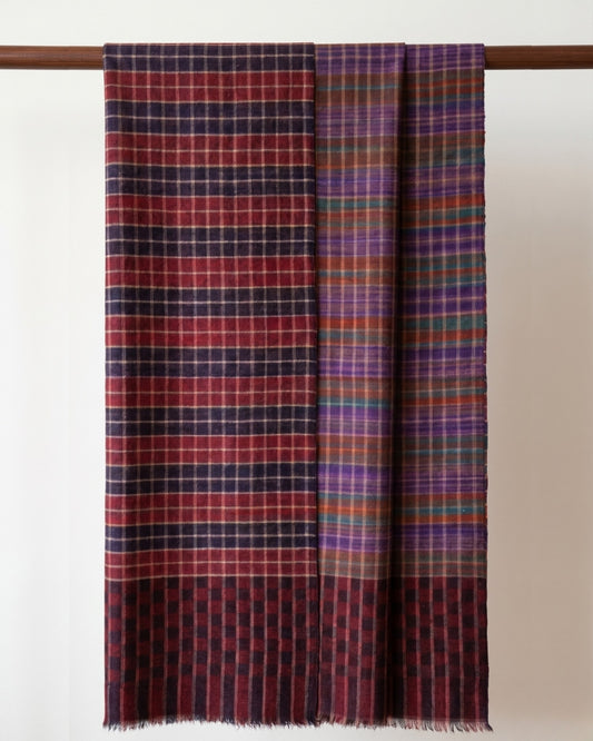 BALI Pashmina über einer Holzstange, mit rot-dunklen Karos und violett-grün-orangefarbenem Muster der Wendeseite