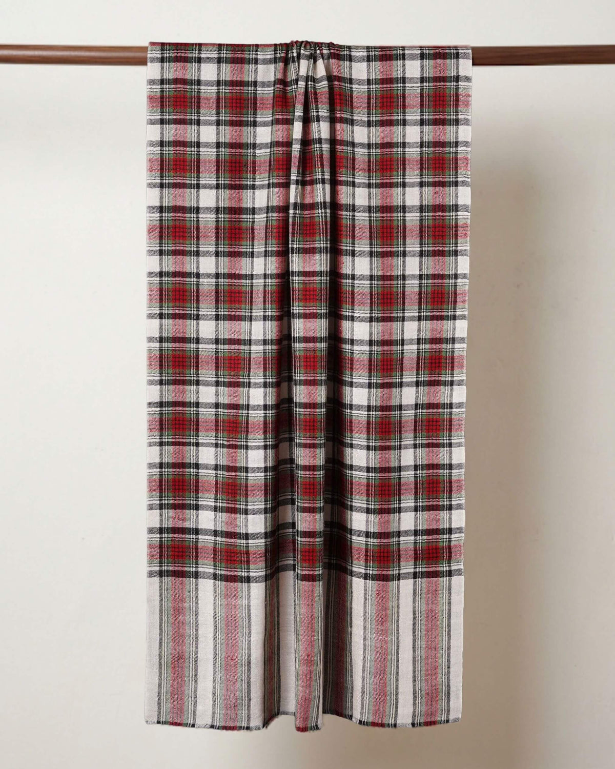 BLAIR Pashmina locker über eine Holzstange drapiert, mit roten Karos und längs gestreiften Enden.