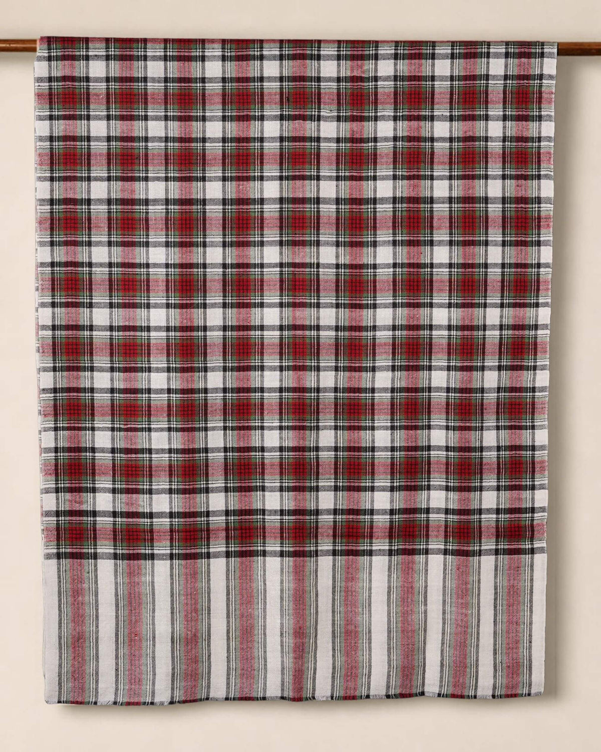 BLAIR Pashmina-Schal mit roten, cremefarbenen und dunkelgrünen Karos, über eine Holzstange gelegt.