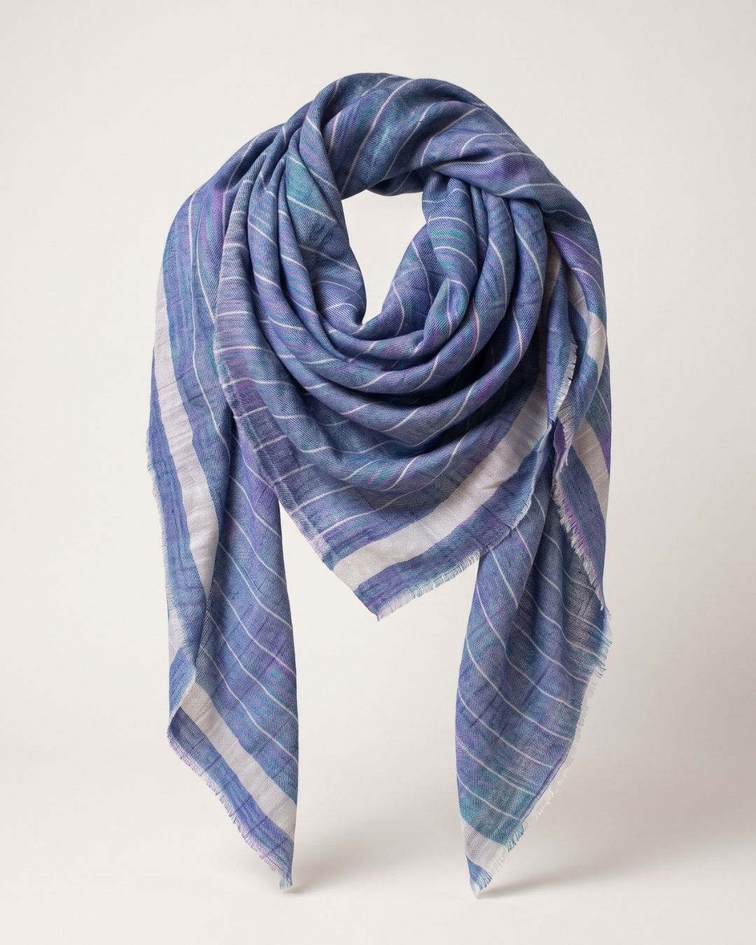 Blaues CHAYE Pashmina-Foulard locker drapiert, mit feinen hellen Karos, heller Bordüre und kurzen Fransen.
