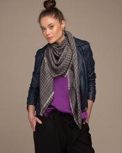 Load image into Gallery viewer, Graues CHAYE Pashmina-Foulard mit feinen hellen Karos, getragen zur dunkelblauen Lederjacke und violettem Oberteil.
