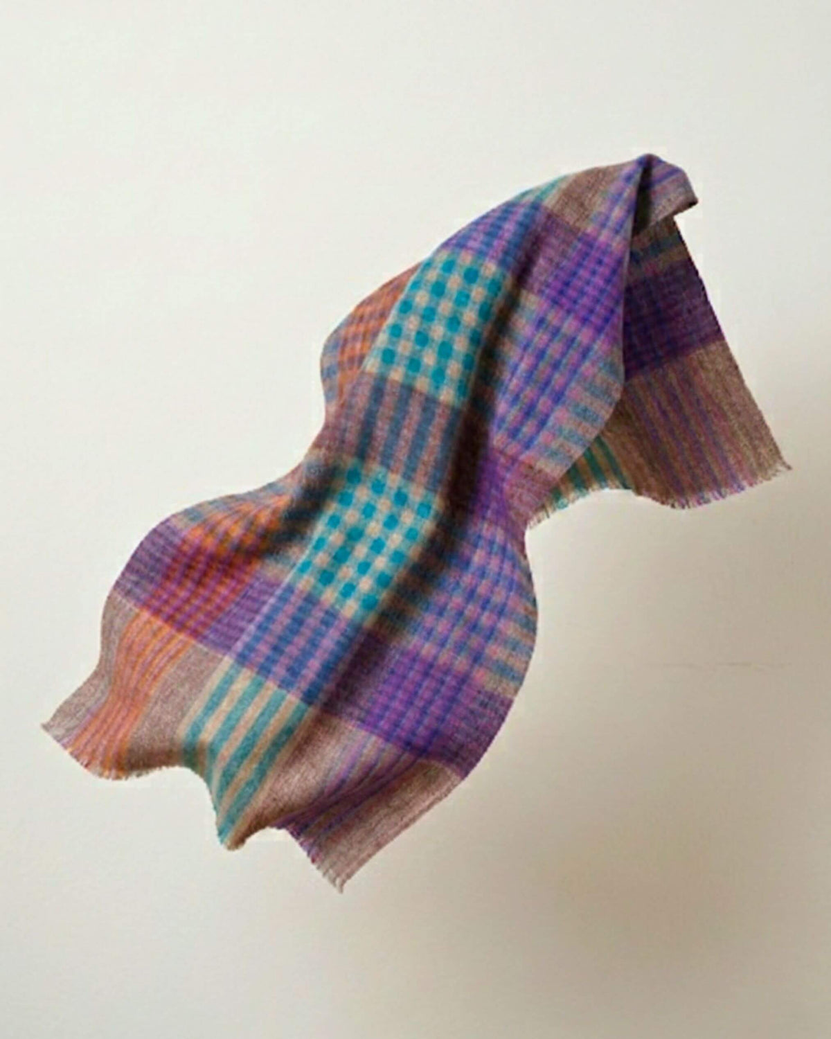 FEZZ Pashmina-Schal in schwebender Drapierung, mit türkis-violetten Karos, orangefarbenen Akzenten und Fransen.