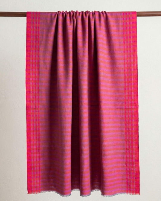 HARI Pashmina mit Streifen in Pink, Orange und Violett und karierten Rändern, über eine Holzstange gelegt