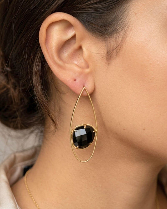 INDU Ohrring mit facettiertem schwarzem Onyx und goldfarbener Tropfenform am Ohr getragen.