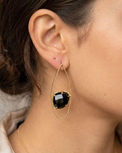 Charger l'image dans la visionneuse de la galerie, INDU Ohrring mit facettiertem schwarzem Onyx und goldfarbener Tropfenform am Ohr getragen.
