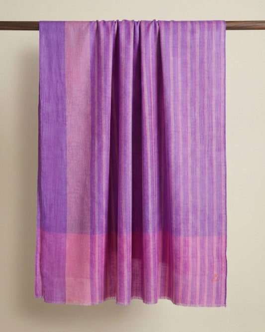 LILOU Pashmina-Schal in Flieder und Rosé mit feinen Streifen, längs über eine Holzstange gelegt.