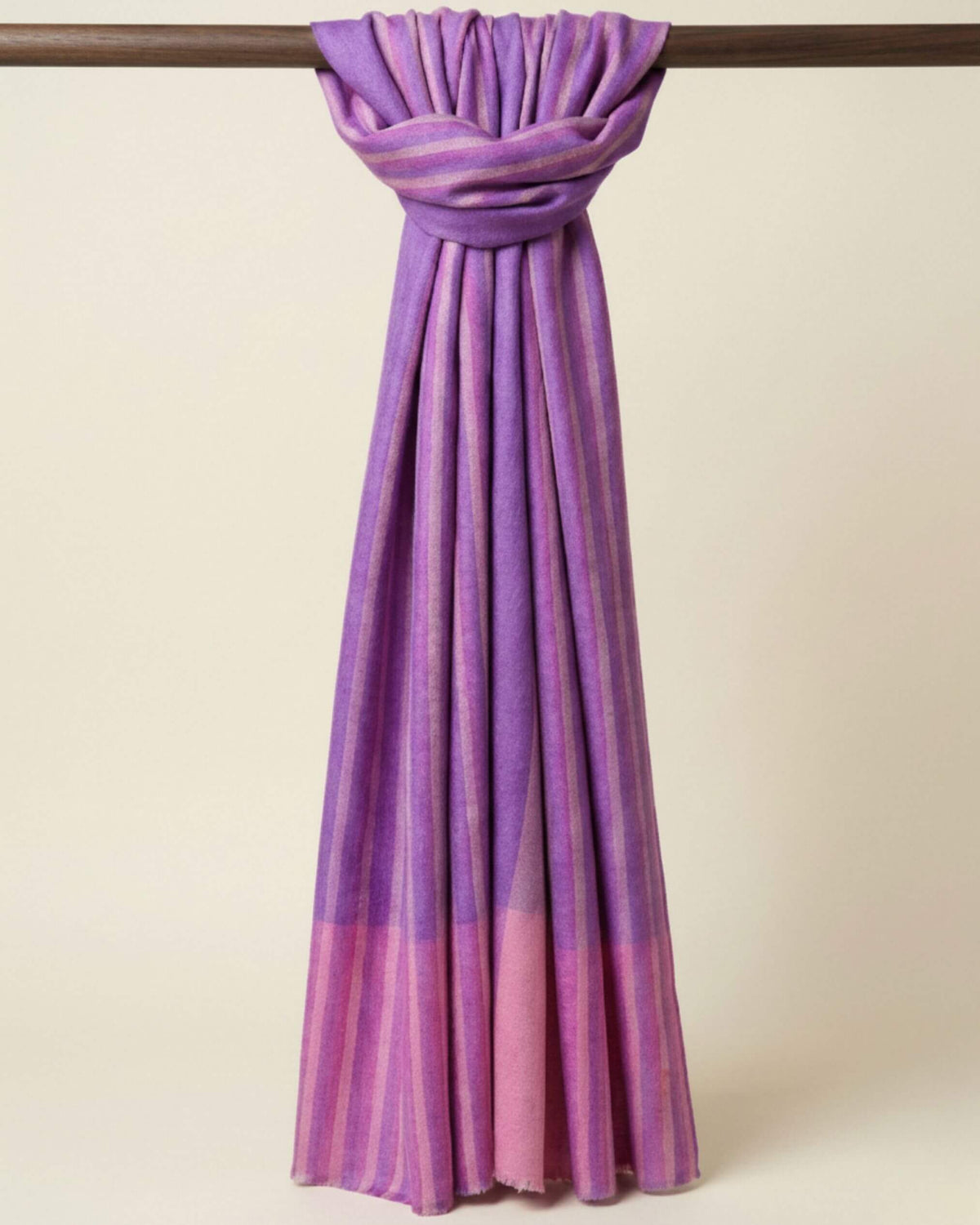 LILOU Pashmina-Schal in Flieder und Rosé, im Schlaufenknoten um eine Holzstange gelegt.
