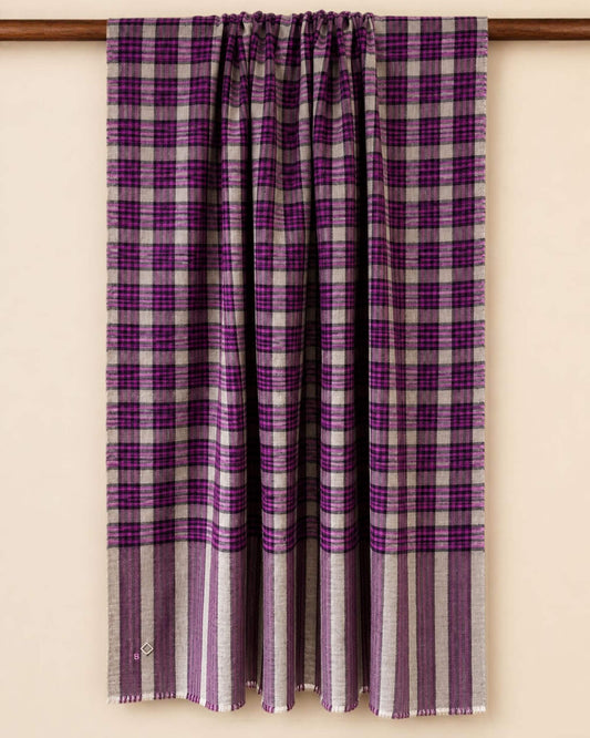 MORIX Pashmina-Schal über einer Holzstange, mit Karos in Beige, Magenta und Violett und gestreiften Enden.
