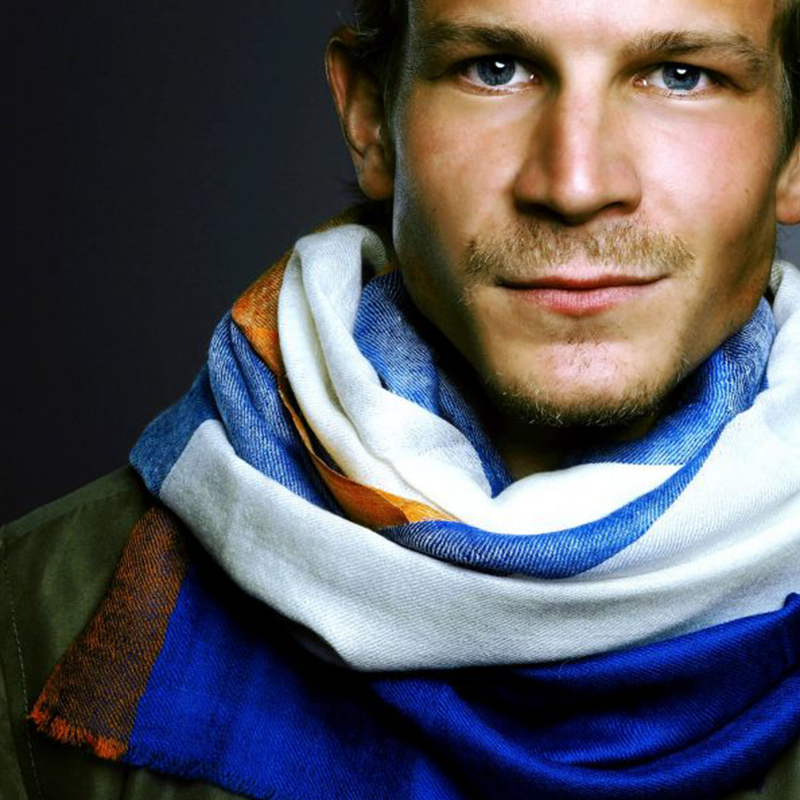 NITRA Pashmina Herrenschal in Blau, Weiss und Orange, locker um den Hals getragen.
