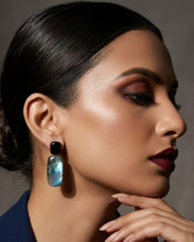 Charger l'image dans la visionneuse de la galerie, NYRA Ohrring mit schwarzem Onyx und blau schimmerndem Labradorit, getragen zu einem dunkelblauen Outfit bei hochgestecktem Haar.
