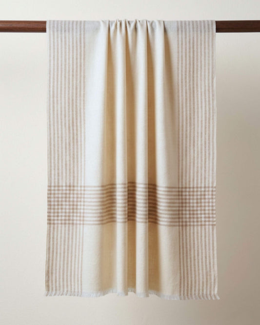 OPUS Pashmina in Creme mit beigebraunen Streifen und Karos, über eine Holzstange gelegt.