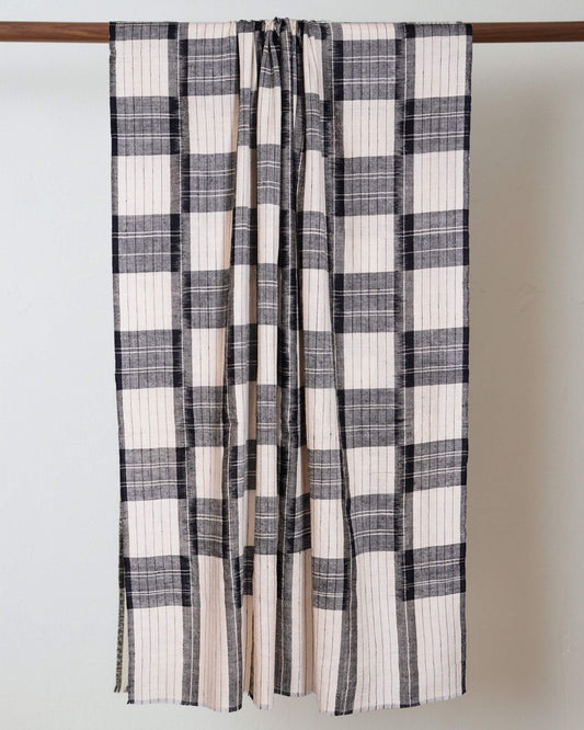 ROMMA Pashmina mit grossen Karos in Creme, Grau und Schwarz, über eine Holzstange gelegt.