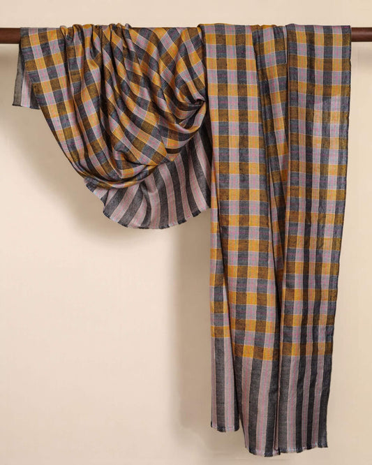 VIRAT Pashmina mit senfgelb-grauen Karos, rosa Linien und gestreiften Enden, über eine Holzstange drapiert.