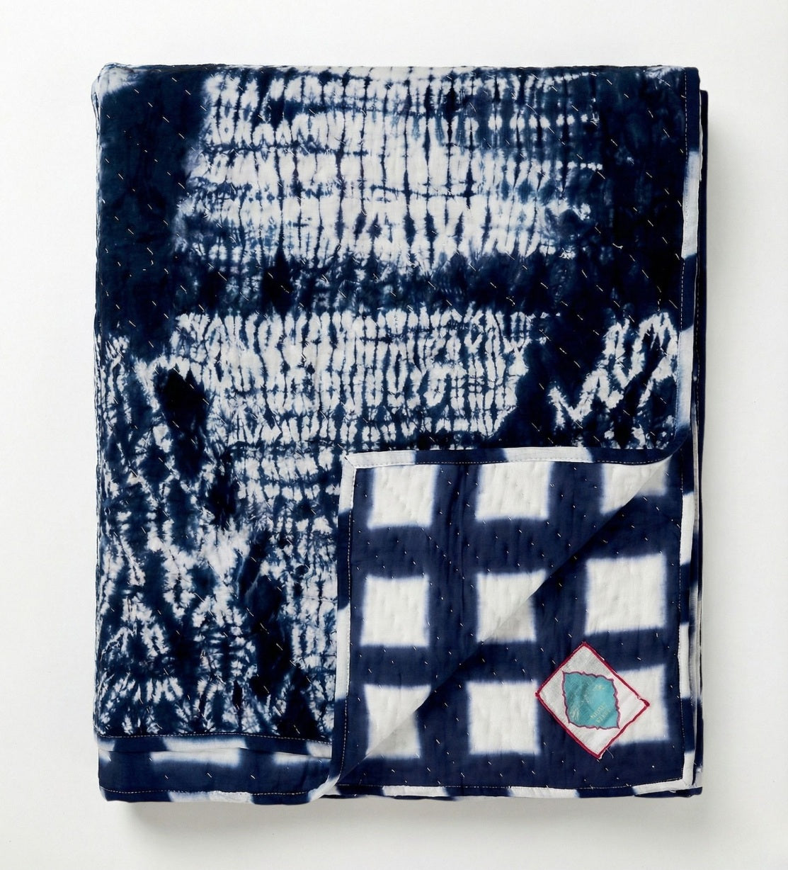 Detail der kontrastreichen Wende-Decke – bietet die Wahl zwischen einem grafischen Raster Shibori-Formen in Indigo.
